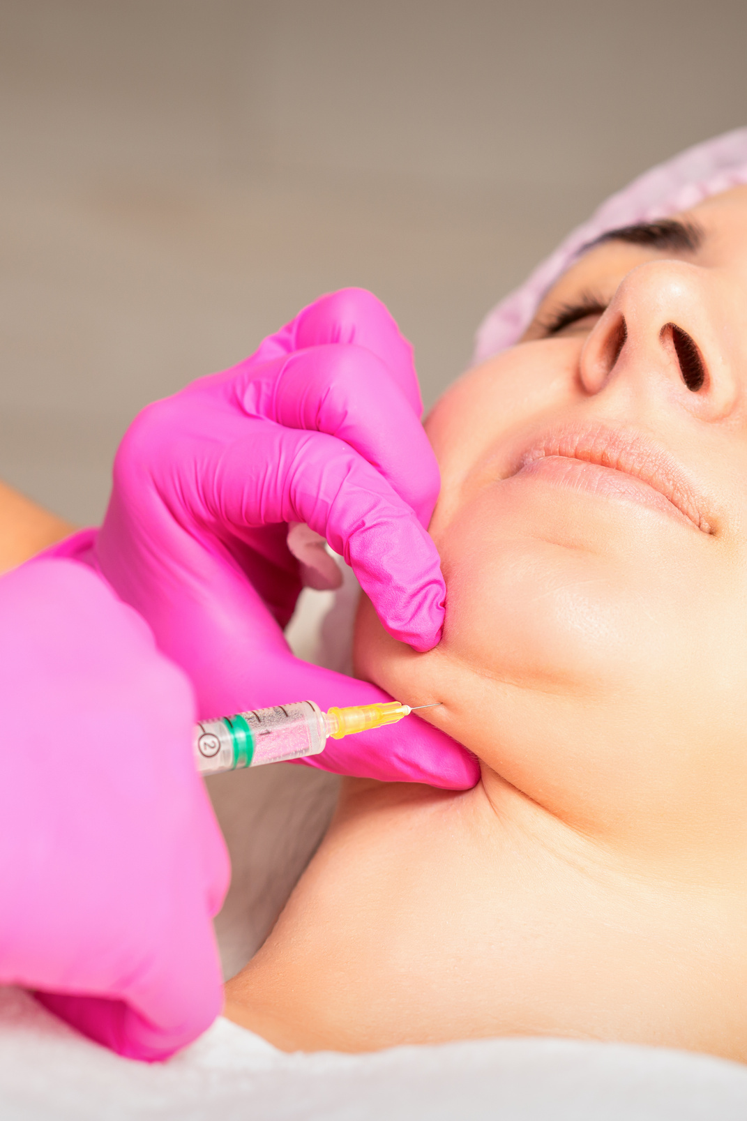 The Cosmetologist Makes Lipolytic Injection on the Chin of a Young Woman against the Double Chin in a Beauty Salon.